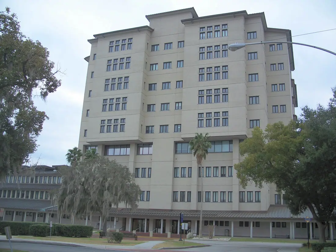 A low modern government building with tall columns and a wide plaza, photographed from the street.