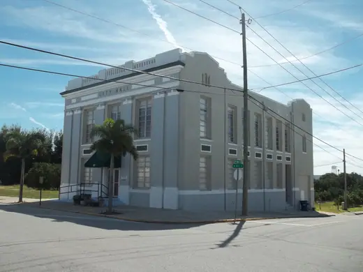 A small single-storey masonry civic building with an arched entrance on a quiet street corner.