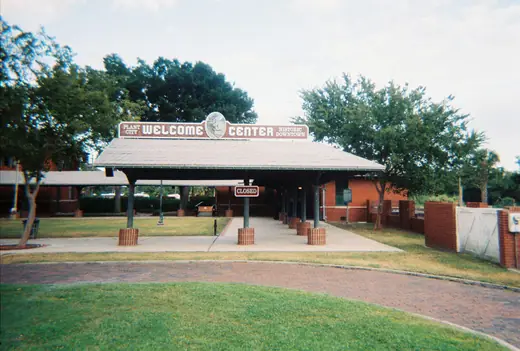 A restored brick railroad depot with a deep overhanging roof beside a set of tracks.