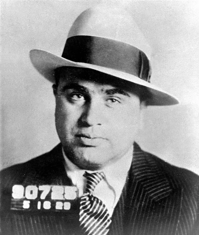 Black-and-white police photograph of a heavy-set man in a suit and tie, facing the camera.