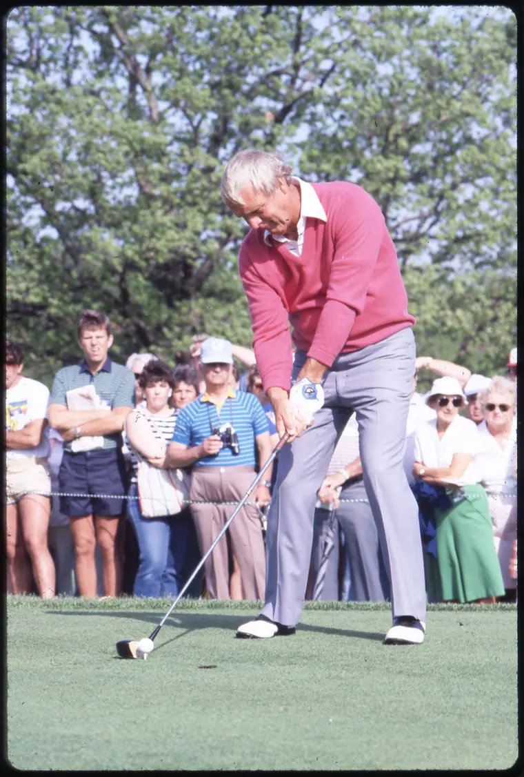 Golfer in a dark shirt preparing to hit a tee shot as spectators watch from behind the ropes.