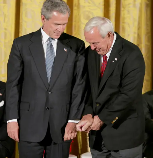 An older man in a suit standing beside the President of the United States at a White House ceremony.