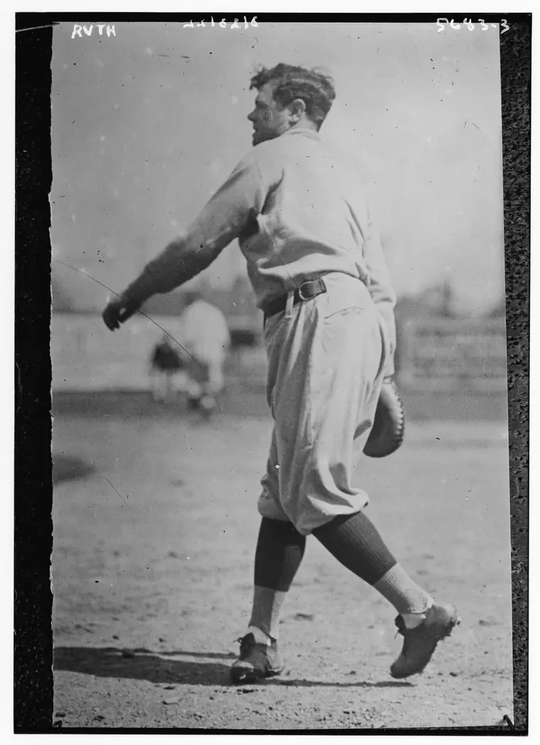 Portrait of a broad-shouldered ballplayer in a pinstriped uniform, cap pushed back, arms folded.