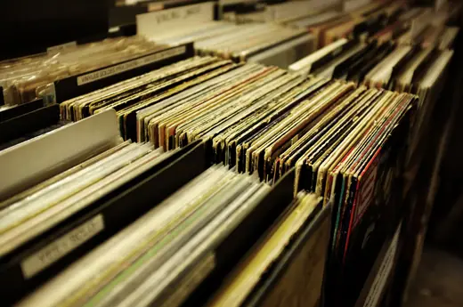 Used vinyl records filed upright on the shelves of a record shop.