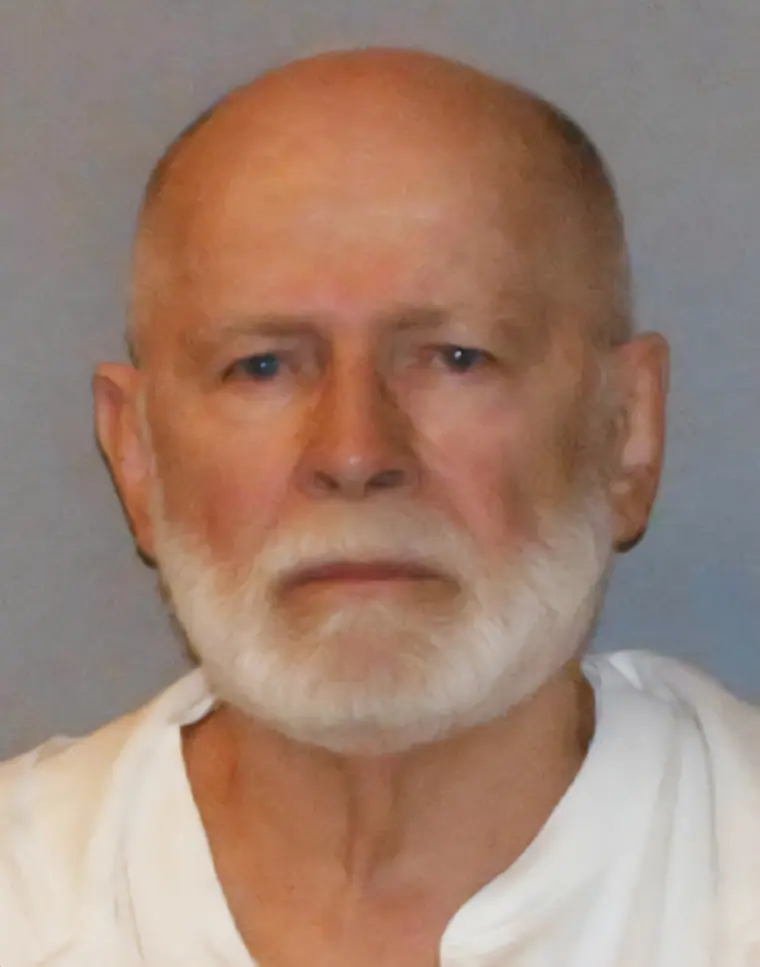 A federal booking photograph of an elderly man in a plain shirt facing the camera.