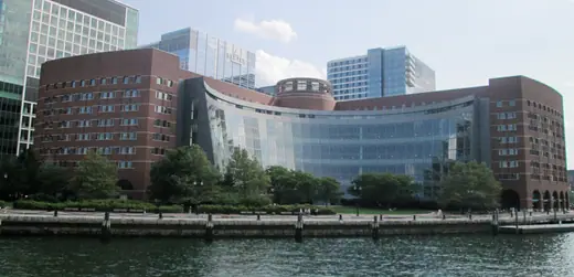 A curved brick and glass federal courthouse on the Boston waterfront, seen from the harbour.