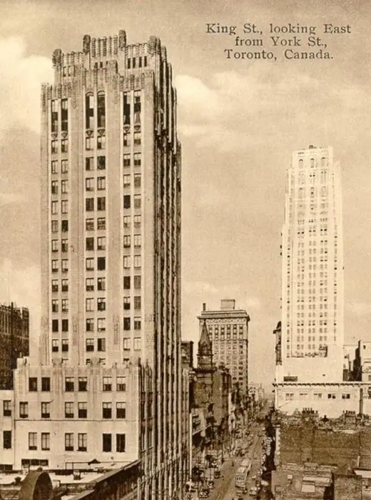 Colour postcard looking down a canyon of office towers with streetcars and pedestrians below.