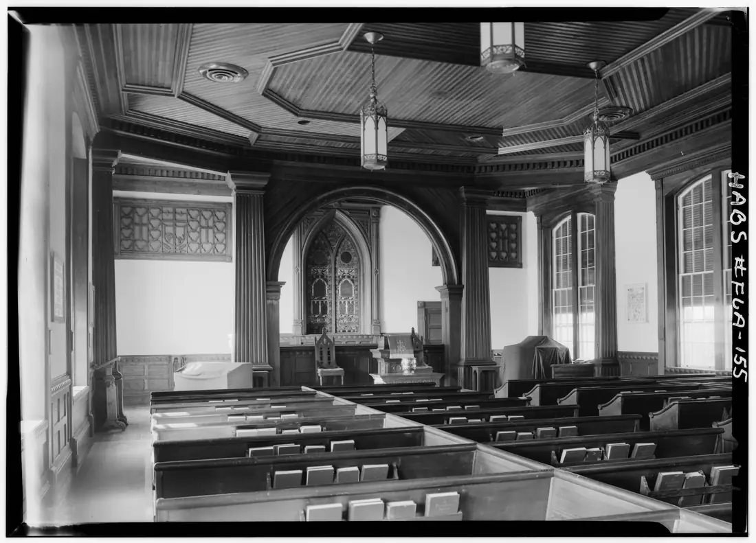 Interior of Monticello Presbyterian Church looking toward the chancel, with wooden pews and tall windows.