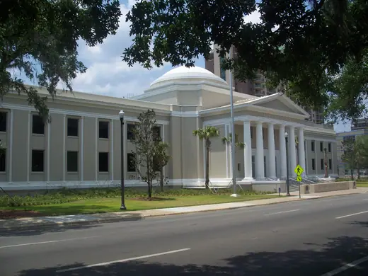 A white neoclassical courthouse with a columned portico and a domed rotunda, seen from the lawn.