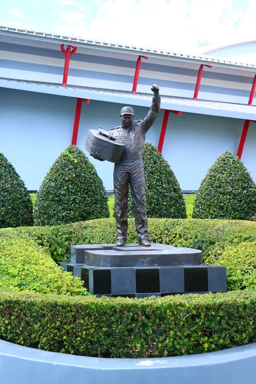 Bronze statue of Dale Earnhardt holding a trophy in front of the Daytona International Speedway Welcome Center.