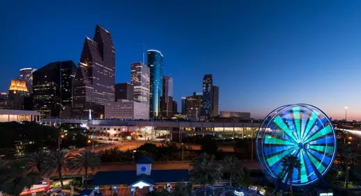 Dusk view of the illuminated Houston skyline photographed from the Downtown Aquarium, with the aquarium's Ferris wheel at right.