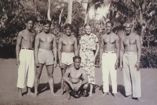 Group photograph of Doris Duke seated among six members of the Kahanamoku family in Hawaii, around 1937.