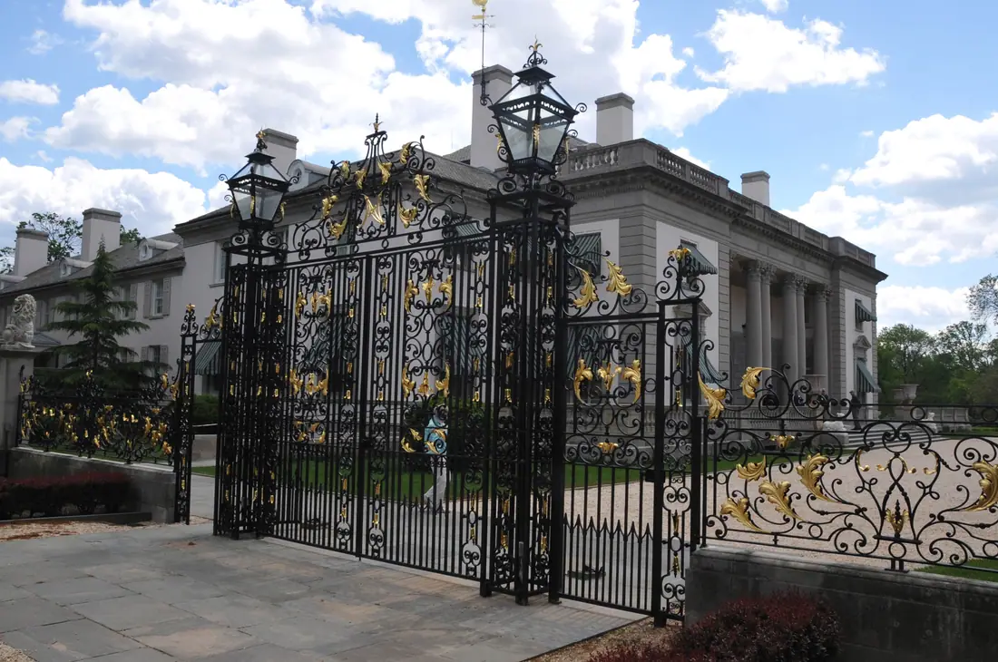 A wide French neoclassical country house of pale stone seen across a formal lawn.