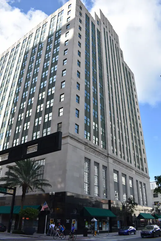 A tall limestone office tower with vertical setbacks rising above downtown streets.