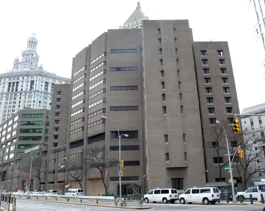 A tall windowless concrete federal detention tower on a lower Manhattan street.