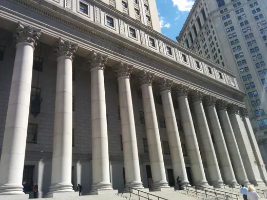 A granite courthouse with a columned portico and a gold-topped tower in Foley Square, Manhattan.