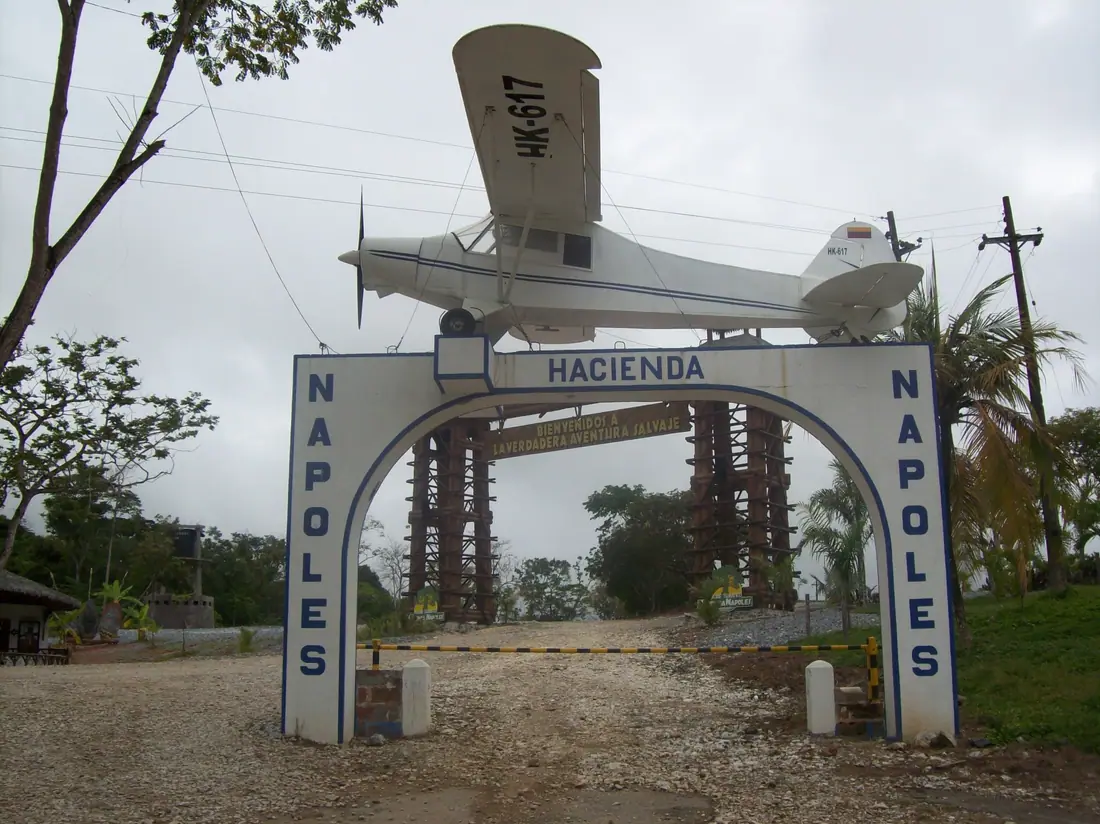 A white concrete entrance gate across a rural road, with a small aeroplane mounted on top of it.