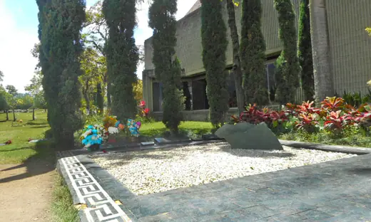 A low family tomb set into a lawn at a hillside cemetery, with flowers on the slabs.