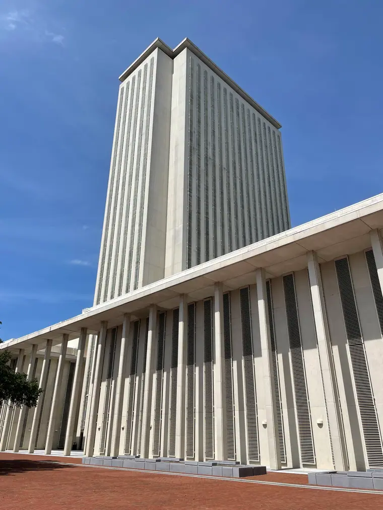 The Florida State Capitol tower in Tallahassee, photographed from ground level against a clear sky.