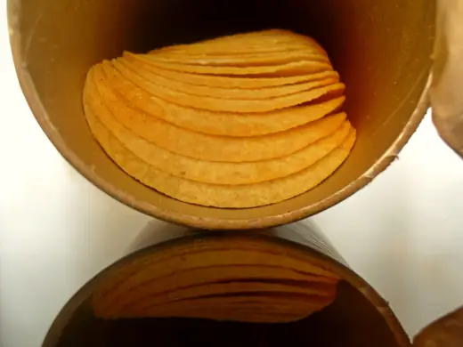 A Pringles tube photographed on a reflective surface.