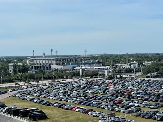 Exterior of a low ballpark with an arched entry facade and palm trees under a bright sky.