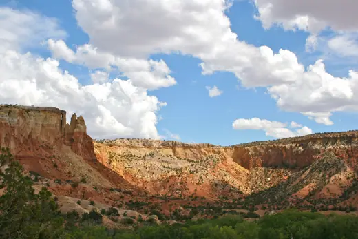 Layered red rock cliffs near Abiquiu, New Mexico, under a bright sky.