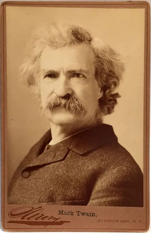 Cabinet-card portrait of Mark Twain in a dark suit with a heavy moustache and unruly hair.