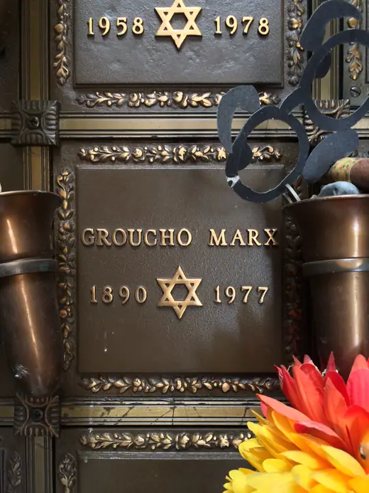 A small memorial plaque set into a wall of a columbarium, photographed in daylight.