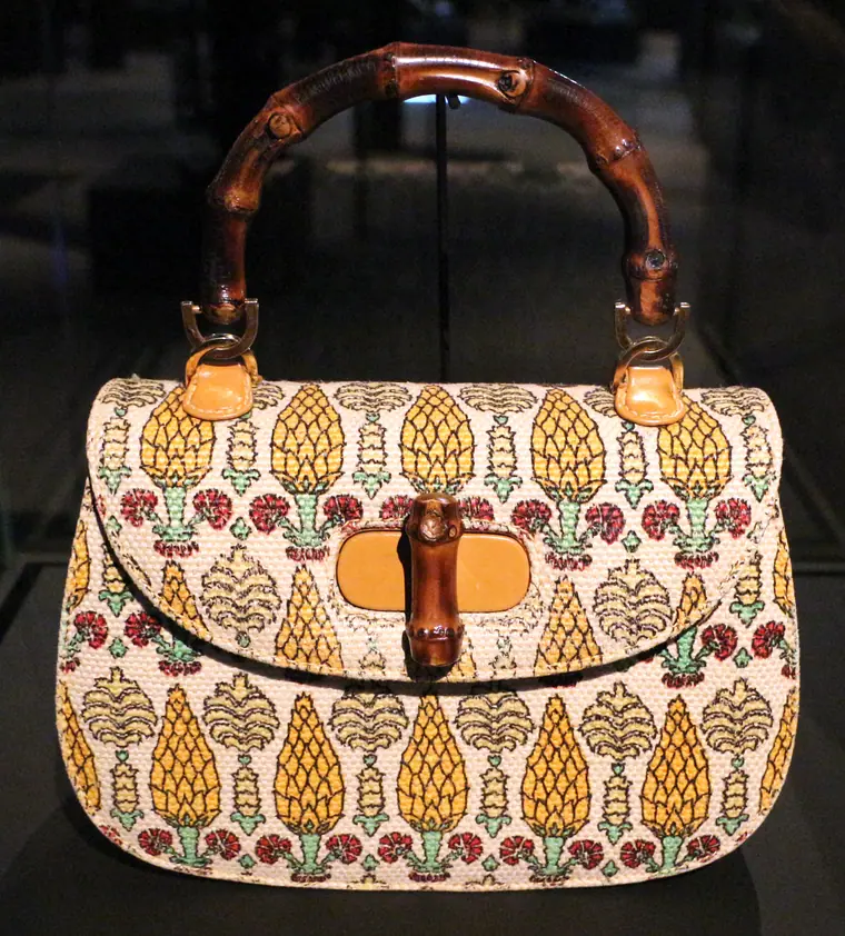A Gucci bamboo-handled handbag from the early 1960s, displayed on a stand.