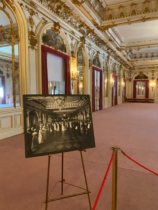 A gilded Louis XV ballroom with painted ceiling, mirrors, and a chandelier.