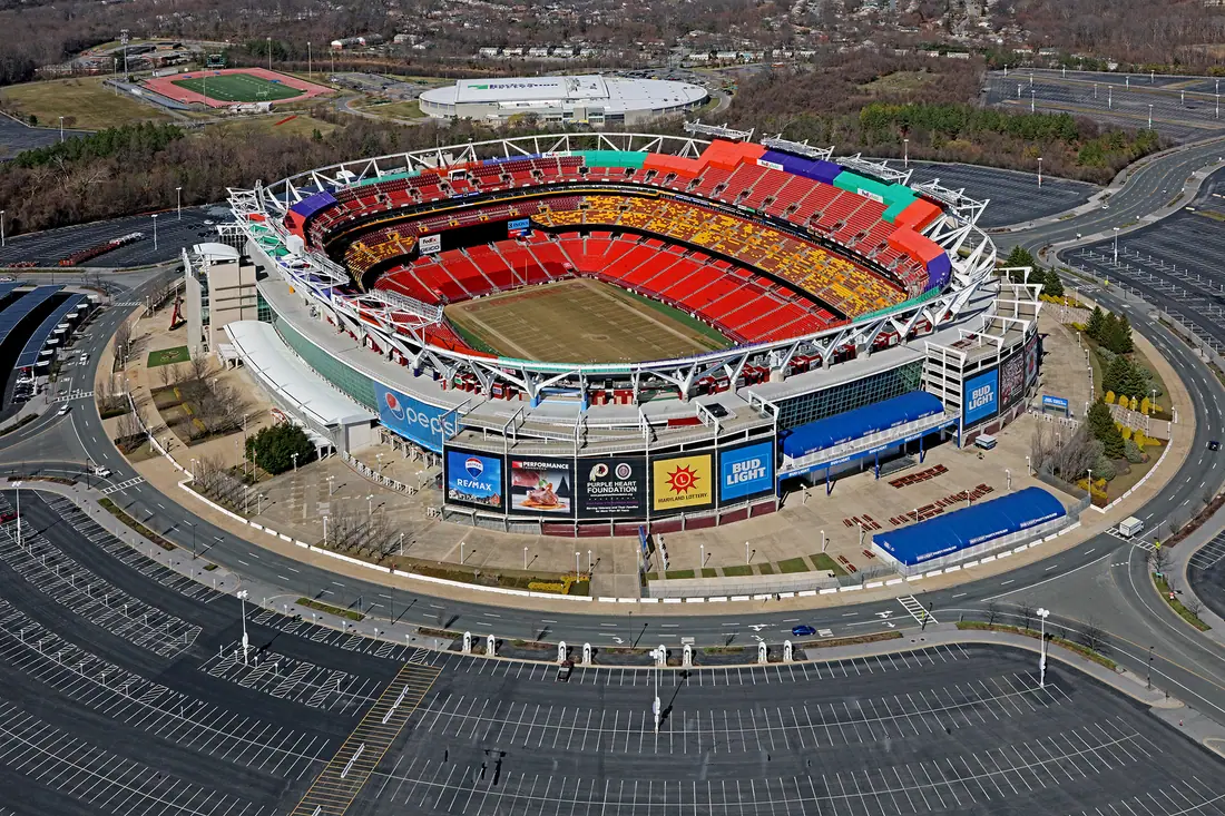 Aerial view of a large open-air American football stadium surrounded by parking lots.