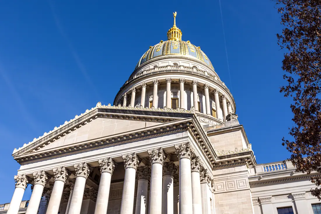 The gilded neoclassical dome of a state capitol building seen against a clear sky.