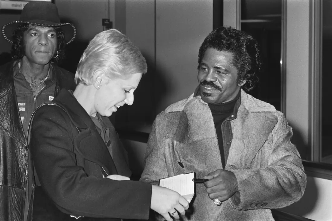 James Brown in a fur-collared coat arriving at Schiphol Airport, Amsterdam, January 1977.