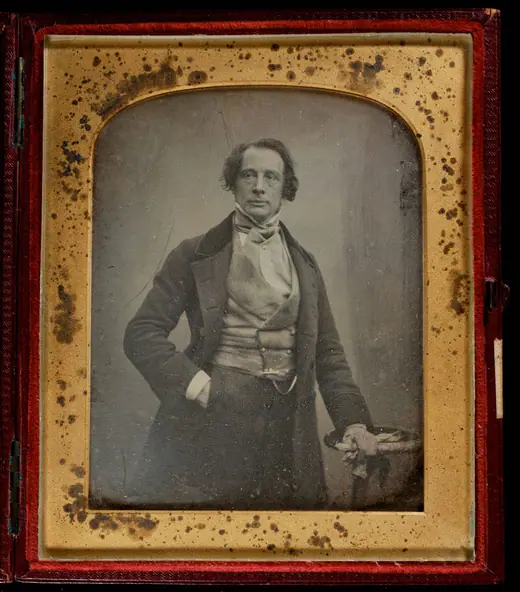 Early photographic portrait of a seated man in his forties with long hair and a beard-less face, wearing a dark coat and patterned waistcoat.