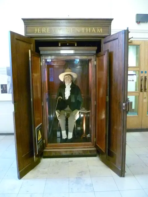 The Auto-Icon in its earlier wooden and glass cabinet in a college cloister.