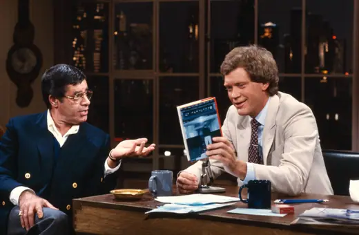 Two men talking on a television set in 1982.