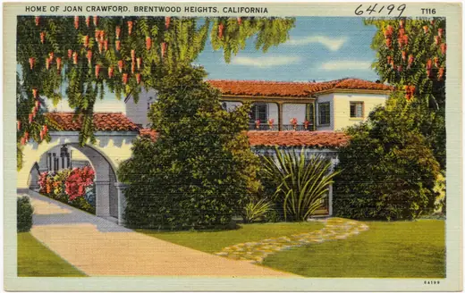 Colour postcard of a white two-storey house behind a lawn and hedges in Brentwood, California.