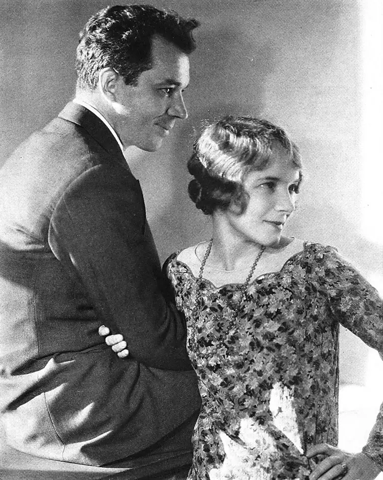 Studio portrait of playwright Charles MacArthur seated beside actress Helen Hayes.