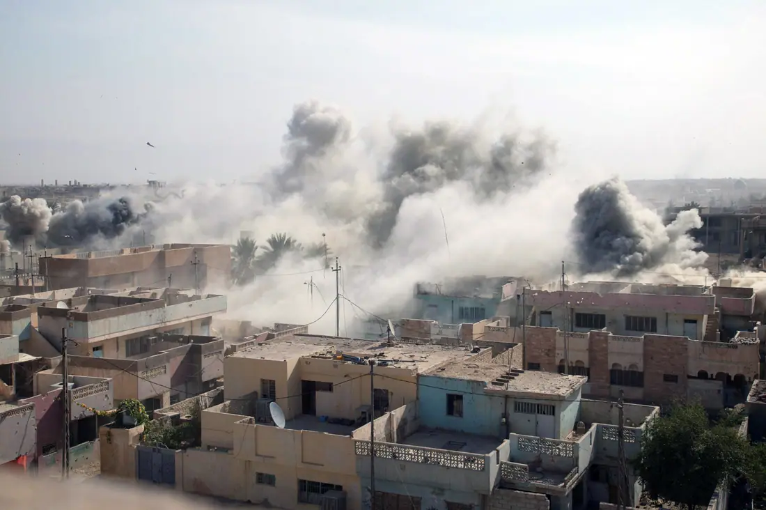 Smoke rising over the low rooftops of Fallujah, Iraq, in November 2004.