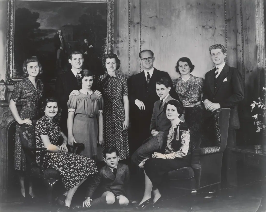 Formal group photograph of the Kennedy family arranged in a drawing room at the London embassy residence.