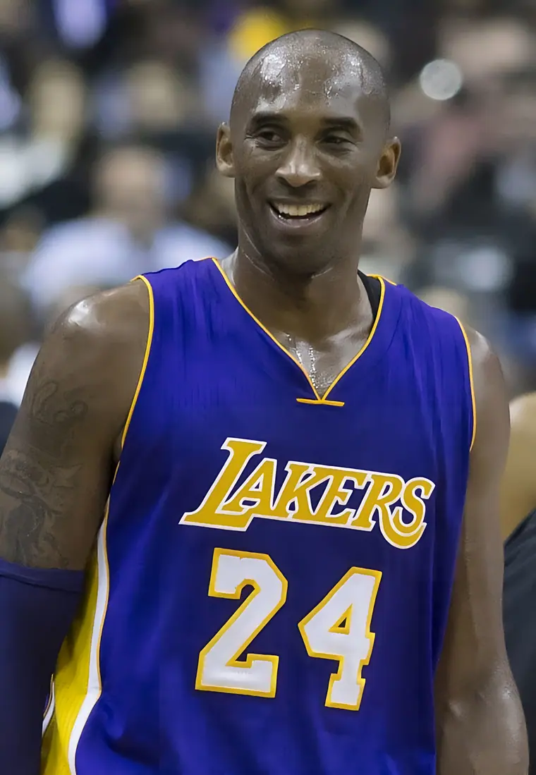 Basketball player in a Lakers uniform standing on court, hands on hips, during a game.