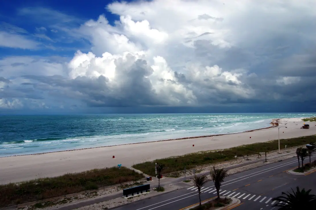 Wide empty white-sand beach on the Gulf of Mexico under a bright sky.