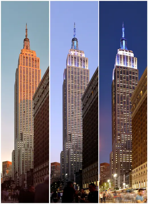 The Empire State Building rising above Manhattan rooftops at dusk with its mast lit.