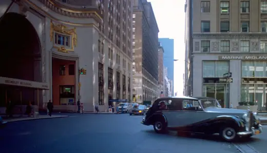 A Rolls-Royce parked on Park Avenue in front of a stone tower with a gilded clock and crown.