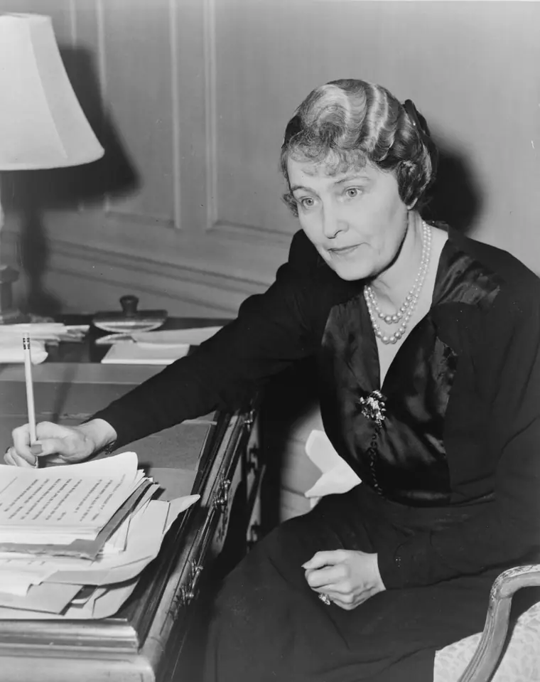Marjorie Merriweather Post seated at a desk, writing, in a 1942 press photograph.