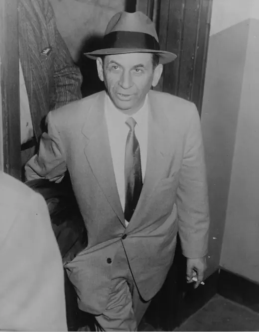 Black-and-white press photograph of a slight, middle-aged man in a suit, photographed at close range.