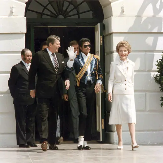 President Ronald Reagan and First Lady Nancy Reagan standing with Michael Jackson on the White House grounds.