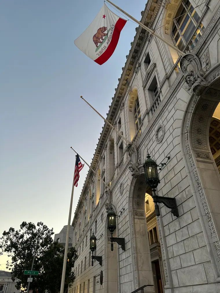 The stone entrance of the Earl Warren Building in San Francisco, with tall arched doorways beneath a carved cornice.