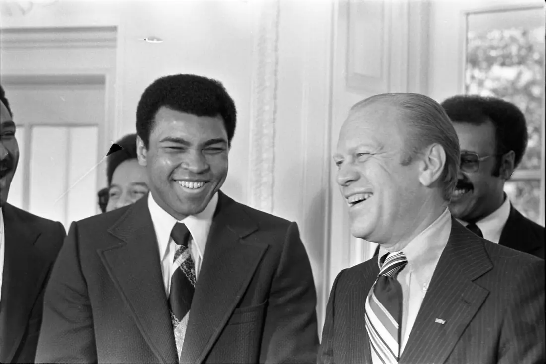 A boxer in a suit talking with the President of the United States in the Oval Office.