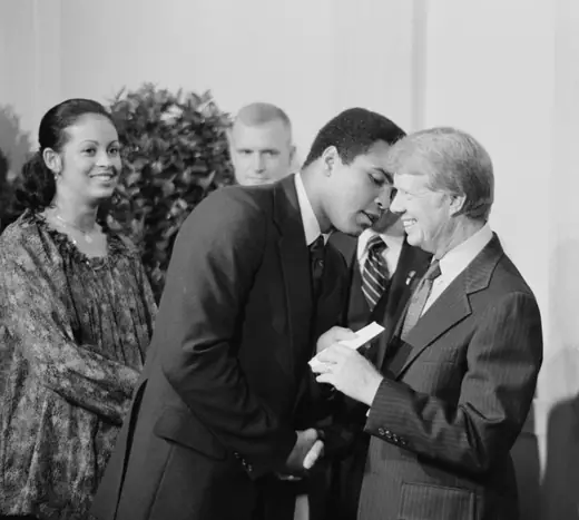 President Jimmy Carter greeting a tall man in a dark suit at a formal White House event.
